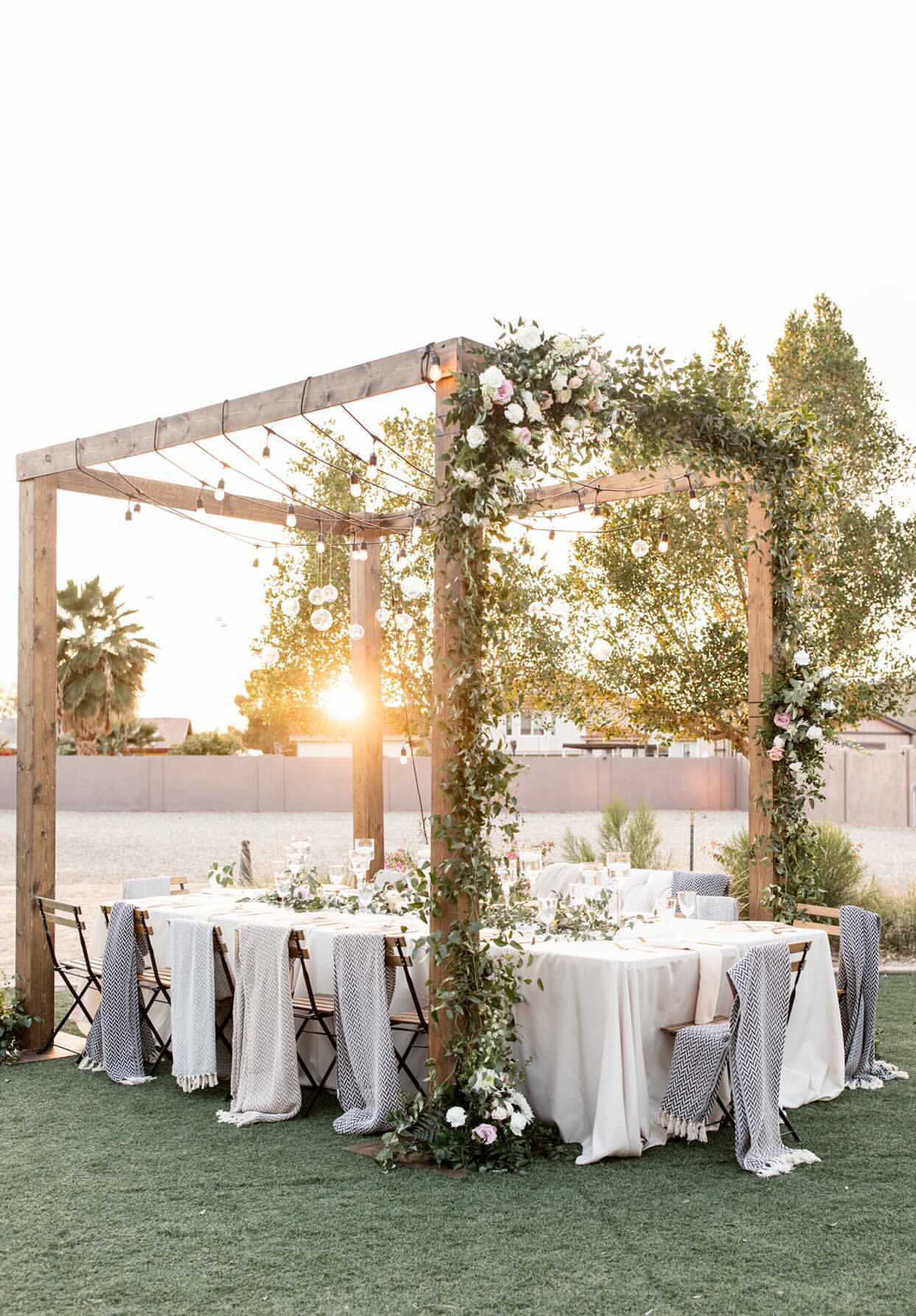 Wedding reception table beneath a floral-covered outdoor pergola